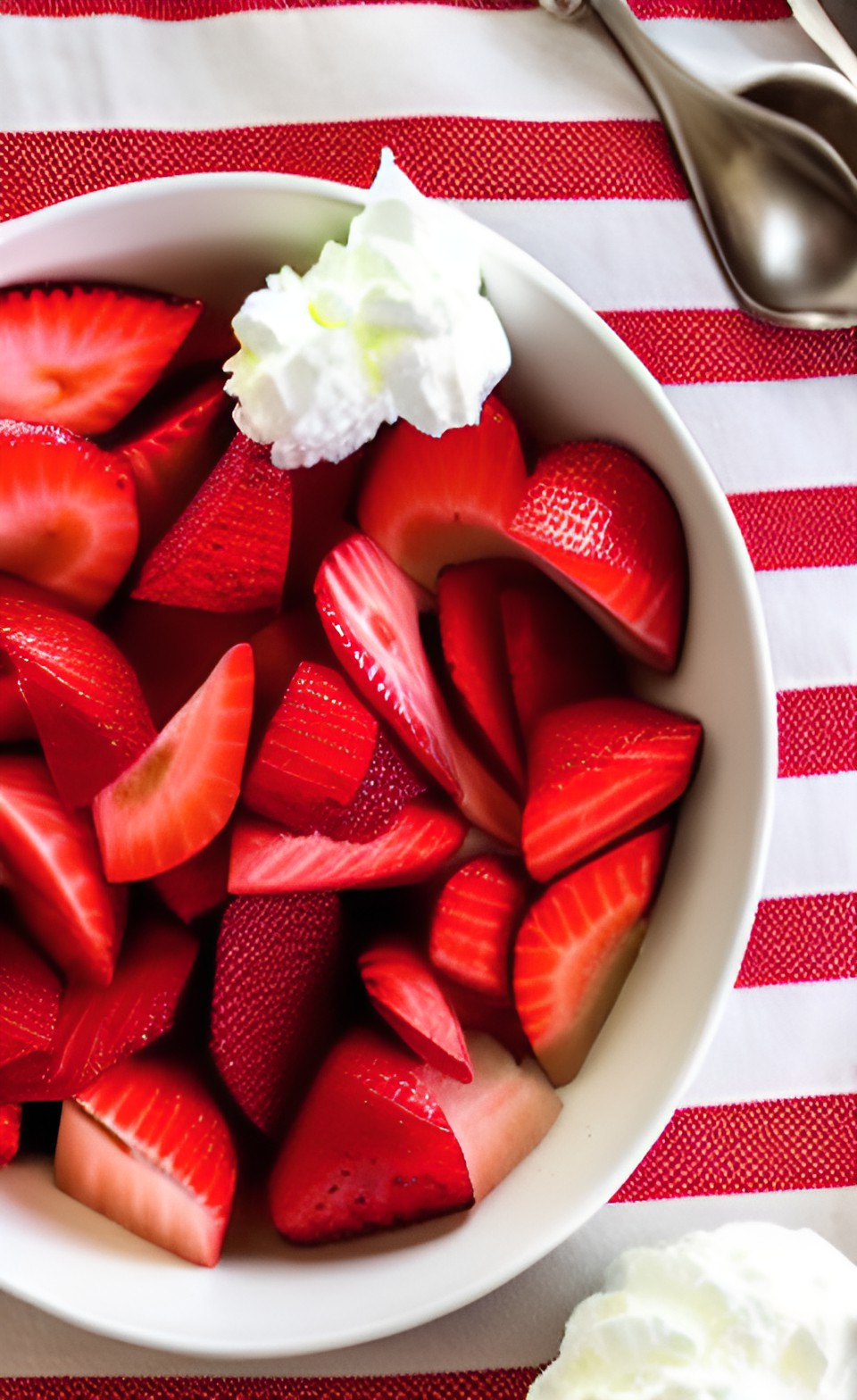 sliced strawberries and cream in a fancy bowl on a table with a red and white checkered tablecloth preview