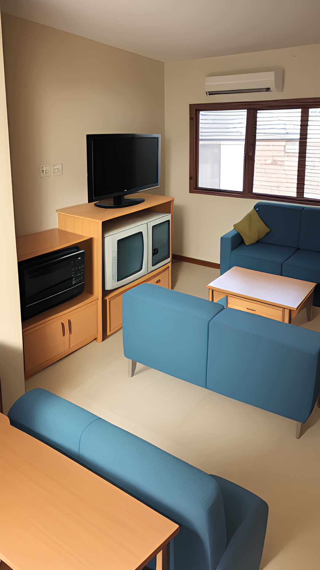 a room with a few chairs a sofa a small table a tv and a microwave oven preview